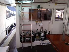 Interior view of the helm area on the Oceania boat, showcasing the organized space with scuba tanks and a ladder leading to the upper deck.