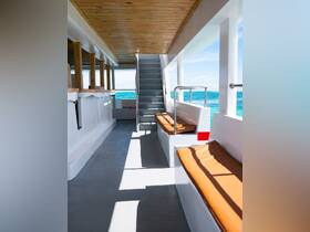 Interior view of a spacious boat cabin featuring comfortable seating and a staircase leading to the upper deck, perfect for relaxing while enjoying the ocean views.
