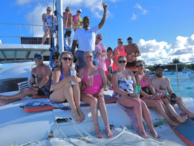 A lively group enjoys a fun day aboard a catamaran, celebrating with cocktails and soaking up the sun — perfect for memorable outings on the water.