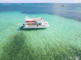 A stunning aerial view of a Malibu boat cruising through crystal-clear turquoise waters, perfect for exploring beautiful coastal destinations.