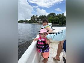 Two young children in life jackets enjoy a boat ride, showcasing a fun family outing on the water.