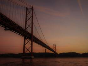 A scenic view of a bridge at sunset, capturing the silhouette against a colorful sky. The image lacks clarity and detail.