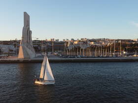 A picturesque view of a sailboat gliding past a prominent landmark in the city, showcasing the vibrant marina and urban backdrop — perfect for sailing enthusiasts and city explorers.