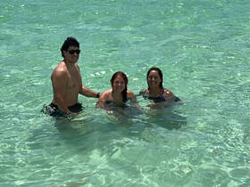 A joyful group enjoys a refreshing swim in crystal-clear waters, perfect for a fun day at the beach.