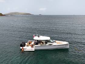 A group enjoys a day on the water with one person swimming near a stylish boat, showcasing a perfect blend of relaxation and adventure.