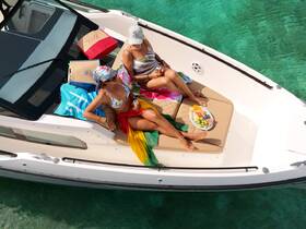 Two friends relax on the deck of a yacht, enjoying a colorful fruit platter and drinks while soaking up the sun — a perfect day on the water.