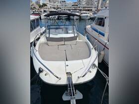 A spacious interior view of a boat's seating area, featuring comfortable cushions and a sleek helm, perfect for relaxing on the water.