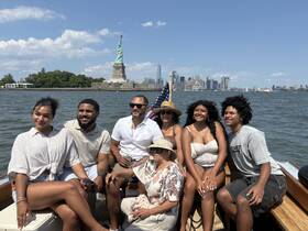 A joyful family poses for a photo on a boat tour near the Statue of Liberty, capturing the essence of a memorable day in New York City.