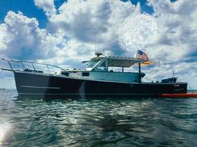 A striking side view of a yacht anchored in calm waters under a cloudy sky, showcasing its sleek design and American flag.