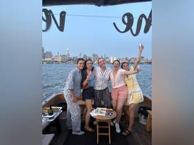 A joyful group of friends celebrates aboard a boat, enjoying cocktails and the stunning skyline backdrop — perfect for bachelorette parties or memorable gatherings on the water.
