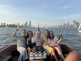 A lively group of friends celebrates on a boat with cocktails, enjoying stunning views of the city skyline — perfect for memorable boat parties and gatherings.