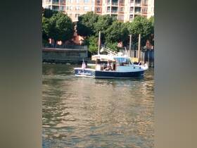 A charming boat named 'Konstantina' glides through calm waters, framed by urban scenery — perfect for leisurely outings or sightseeing.