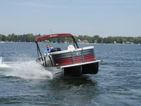 A speedboat glides across the water with a driver at the helm, showcasing the thrill of boating on a sunny day.