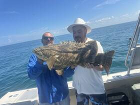 Two anglers proudly display their impressive catch while fishing on a boat, showcasing the thrill of a successful day on the water.