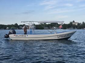 A man waves from the deck of the 'Tarzan II' boat in Isla Mujeres, showcasing the vibrant marine life and scenic views of the area.