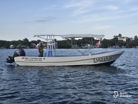 A speedboat named 'Tarzan II' navigates the waters of Isla Mujeres, showcasing its sleek design and vibrant surroundings.