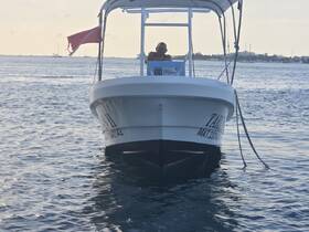 A close-up view of a boat named 'TARAN II' with a person seated at the helm, showcasing its sleek design against the shimmering water.