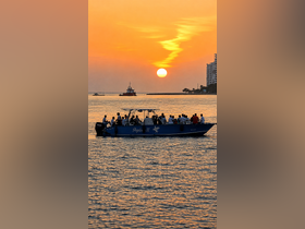 A lively group enjoys a sunset cruise aboard the Pegas II, creating unforgettable memories against a stunning backdrop of vibrant colors in the sky.
