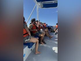 A group of guests wearing life jackets relaxes on the deck of a boat, ready for an exciting adventure on the water.
