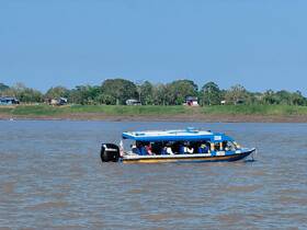 A vibrant speedboat navigates through the river, showcasing its sleek design and passengers enjoying the ride.