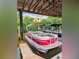 A vibrant red pontoon boat is docked under a covered area, showcasing its spacious seating and inviting design — perfect for leisurely outings on the water.