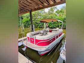 A vibrant red pontoon boat docked under a wooden structure, surrounded by lush greenery — perfect for leisurely outings on calm waters.