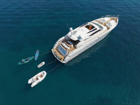 A stunning aerial view of a luxurious yacht anchored in clear blue waters, showcasing its elegant design and surrounding watercraft.