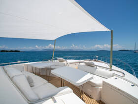 A spacious and stylish lounge area on a yacht, featuring comfortable seating and tables, perfect for relaxing while enjoying the stunning ocean views.