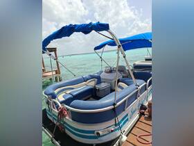Interior view of a comfortable pontoon boat lounge area, featuring plush seating and a cooler, perfect for relaxing on the water.
