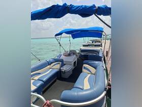 Interior view of a spacious lounge area on a pontoon boat, featuring comfortable seating and a cooler, perfect for relaxing on the water.