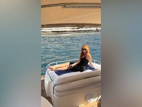 A woman relaxes on the deck of a boat, enjoying the sun and beautiful ocean views — a perfect moment for leisure on the water.