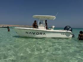 A group enjoys a day at the beach with a boat anchored nearby, showcasing a fun and relaxing atmosphere in clear waters.