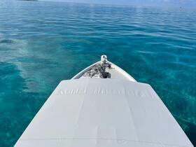 A stunning view from the front of a boat gliding over crystal-clear waters, showcasing the beauty of a serene marine environment.