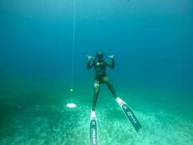 A diver showcases a playful gesture underwater, highlighting the thrill of freediving in crystal-clear waters — an exhilarating experience for adventure seekers.