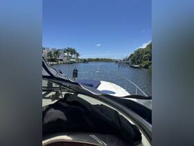 A scenic view from the bow of a boat navigating through a tranquil waterway, surrounded by lush greenery and waterfront homes.