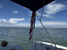 A scenic view from a boat showcasing the water and sky, with a person partially visible enjoying the experience. Perfect for capturing the essence of a day on the water.