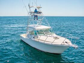 A sleek speedboat navigates through clear blue waters, showcasing its impressive design and a captain at the helm, perfect for fishing or leisure outings.