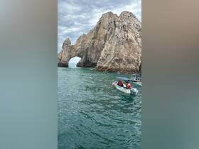 A group enjoys a boat tour near the iconic rock formation at Cabo San Lucas, showcasing the stunning coastal scenery and vibrant marine life.