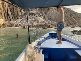 A group enjoys a fun day at the beach, with one person swimming and another on the boat, showcasing a perfect day of relaxation and adventure on the water.