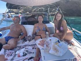 A lively group enjoys a relaxing day on the water, sharing food and drinks aboard their boat, perfect for summer gatherings and fun in the sun.