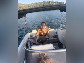 A woman enjoys a sunny day on the water, playfully posing while steering the boat — perfect for capturing joyful moments on a boating adventure.