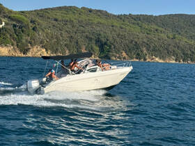 A lively group enjoys a thrilling ride on a speedboat, cutting through the waves against a scenic backdrop of lush greenery.