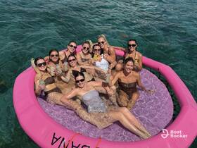 A lively group of friends enjoys drinks and fun on a floating mat in crystal-clear waters, perfect for a memorable day under the sun.