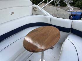 Interior view of a boat's seating area featuring plush white upholstery and a polished wooden table, perfect for relaxing on the water.