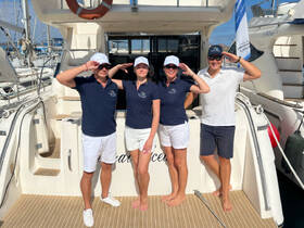 A cheerful group of boat crew members poses on the deck, showcasing camaraderie and readiness for an exciting day on the water.