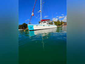 A stunning side view of a catamaran docked in calm waters, showcasing its sleek design against a backdrop of lush greenery and blue skies.