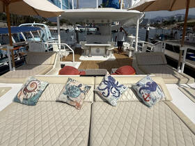 A spacious lounge area on a yacht featuring comfortable seating and decorative pillows, perfect for relaxing while enjoying views of the marina.