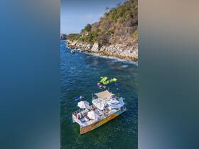 A lively group enjoys various water activities around the 'Tequila Sunrise' boat, showcasing a perfect day of fun in the sun with swimming and paddleboarding.