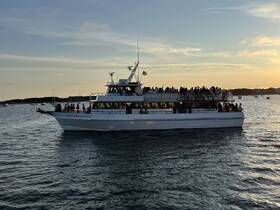 A lively group enjoys a sunset cruise aboard the 'Capt. John & Son II,' creating unforgettable memories on the water.