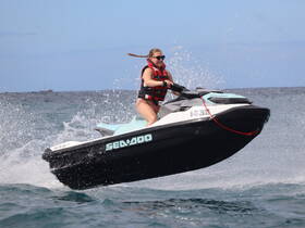 A thrilling moment captured as a woman rides a jet ski, creating splashes in the water — perfect for adventure seekers enjoying water sports.